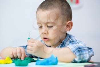 Happy boy playing with color play dough