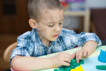 Happy boy playing with color play dough