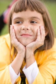 Little girl is daydreaming lying on green grass