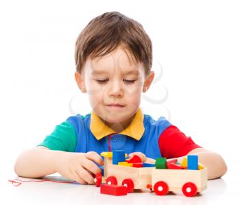 Cute little boy is playing with building blocks, isolated over white