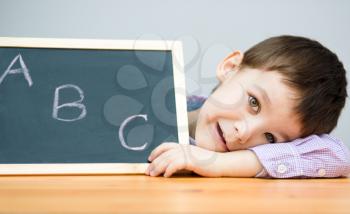 Cute boy is holding blackboard - education concept