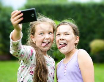 Happy cute girls having fun taking selfie outdoors. together. sisters, friends