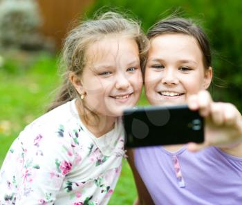 Happy cute girls having fun taking selfie outdoors. together. sisters, friends