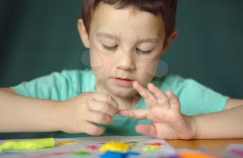 Happy boy playing with color play dough