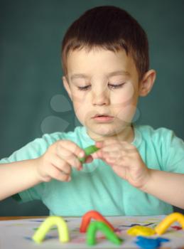 Happy boy playing with color play dough