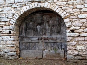 Old antique wooden door or gate. The door in the stone wall cracked.