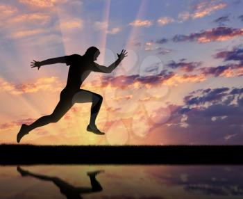 Running sports. Runner athlete and his reflection in the water on the sunset background