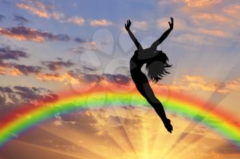 Rainbow and happiness. Happy woman jumping at sunset near the rainbow