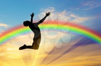 Happiness and success. Happy man jumping on the background of the rainbow in the sky