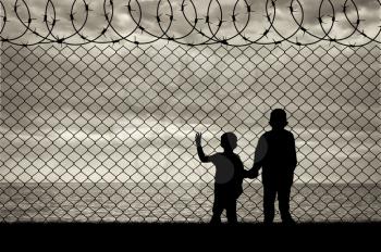 Refugee children concept. Silhouette of two children of refugees near the border on the background seascape