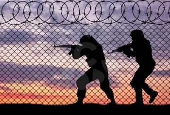 Terrorism and conflict. Armed terrorists near the fence of barbed wire