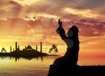 Islamic religion. Muslim praying on a background of a mosque at sunset