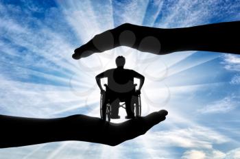 Disabled person in wheelchair in hands on sky background. Concept protection of disabled persons