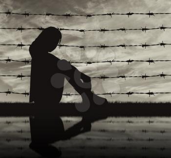 Concept of refugee. Silhouette Despair refugee woman near the fence of barbed wire and reflection
