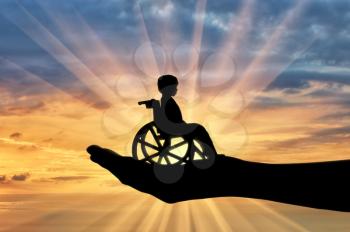 Disabled child in a wheelchair in a man's hand. Concept of care and help