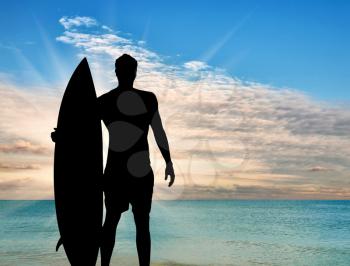 Sports concept. Silhouette of a surfer on the beach at sunset sea background