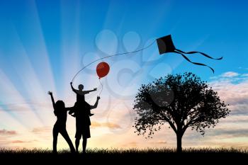 Young family near tree playing with kite and child holding a balloon. Concept happy family