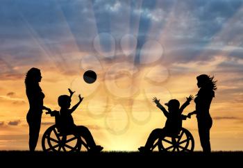 Happy boys in wheelchair play ball and nurses sunset. Concept happy children with disabilities