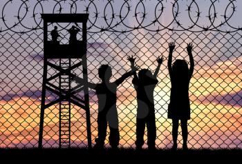 Concept of refugee. Silhouette of the hungry children of refugees at the border fence at sunset and watchtower