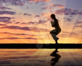 Concept of meditation and relaxation. Silhouette of a man practicing yoga at sunset and reflection in water