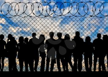 Concept of the refugees. Silhouette of a crowd of refugees at the border at sunset
