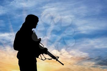 Concept of terrorism. Silhouette of a terrorist with a rifle on a background of a sunset