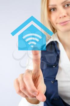 Wireless Internet concept. Business woman clicks on the icon Wi fi in the house