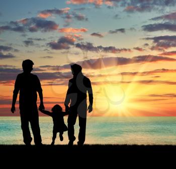?oncept of gay parents. Silhouette of parents of gays and baby girl walking near the sea at sunset