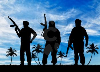 Silhouette of three terrorists with a weapon against a background of blue sky and palm trees