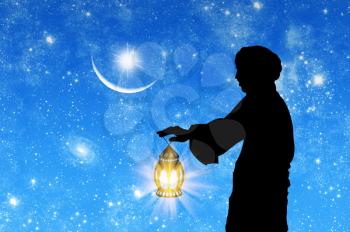 ?oncept of Islamic culture. Silhouette of a man with a lamp in his hand against the background of the starry sky and the moon