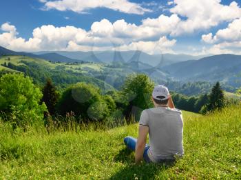 Man resting on top of a mountain on the background of mountain scenery. Summer season