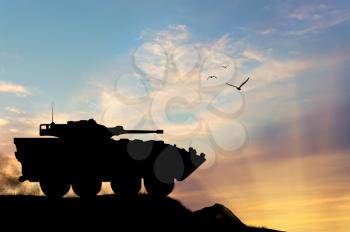 ?oncept of war. Silhouette military APCs at sunset