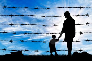 Concept of refugee. Silhouette of hungry refugees mother and child near the fence of barbed wire