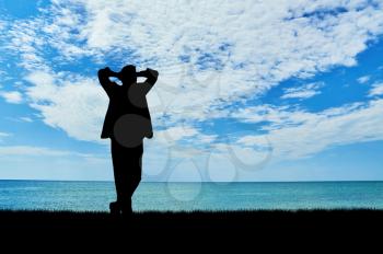 Silhouette of a businessman resting on a background of the sea coast