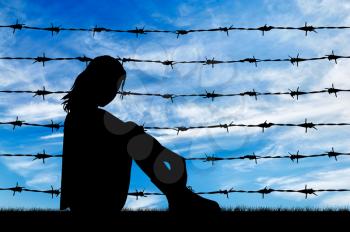 Concept of refugee. Silhouette Despair refugee woman near the fence of barbed wire