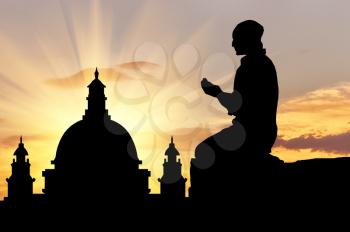 Concept of religion is Islam. Silhouette of man praying at sunset, and the mosque