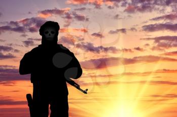concept of terrorism. Silhouette of a terrorist with weapons and a skull face at sunset