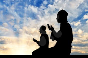 Concept of religion Islam. Silhouette of two men praying at sunset