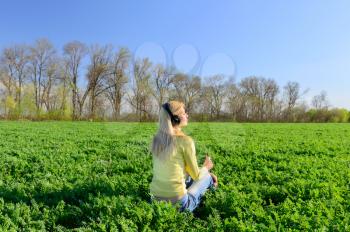 Concept of music. Young woman with headphones listening to music on meadow