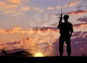 Silhouette of a terrorist with weapons near the helicopter at sunset. The concept of terrorism and war