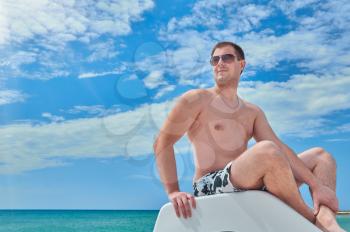 Young man in sunglasses resting on the beach. beach recreation and tourism concept