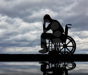 Silhouette of sad man crying in the disabled wheelchair. The concept of people with disabilities experiencing grief for the loss of health