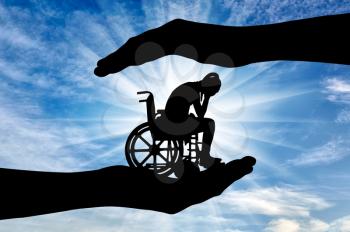 Silhouette of sad disabled woman in wheelchair in hands of help. The concept of protection and assistance to people with disabilities