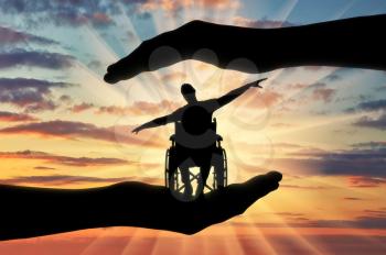 Silhouette of happy disabled man in wheelchair in hands of help. The concept of protection and help to people with disabilities