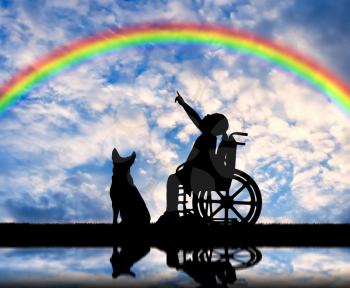 Silhouette of a happy child with a disabled girl sitting in a wheelchair with her dog showing a finger at the rainbow. The concept of the life of children with disabilities