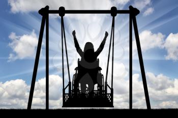 Silhouette of a happy woman is a disabled person in a wheelchair on an adaptive swing for disabled people. The concept of the lifestyle of people with disabilities