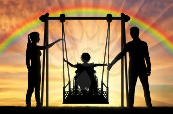 Silhouette of a happy child is a disabled person in a wheelchair on an adaptive swing. Mom and Dad swing it. The concept of the lifestyle of children with disabilities