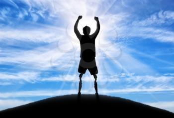 People with disabilities concept. Happy disabled man with a prosthetic leg standing on top of a hill against the sky