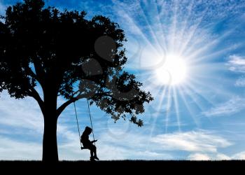 Silhouette of little girl reading a book sitting on a swing on a sunny day. Conceptual image