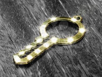 Beautiful glow Golden key lies on the black-and-white wooden background.